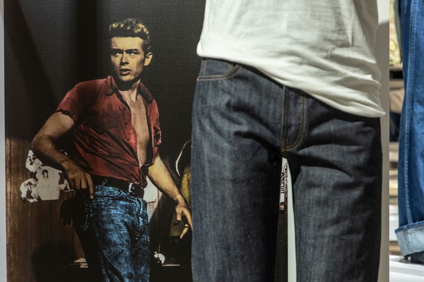 Jeanshose. Im Hintergrund ein Bild von James Dean in Jeans und roter Jacke.