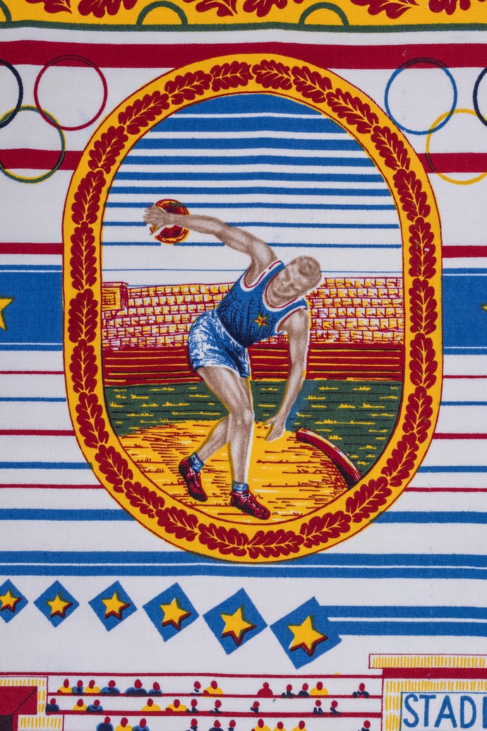In der Mitte des Stoffes ist ein Sportler zu sehen, der eine Wurfscheibe in der Hand hält