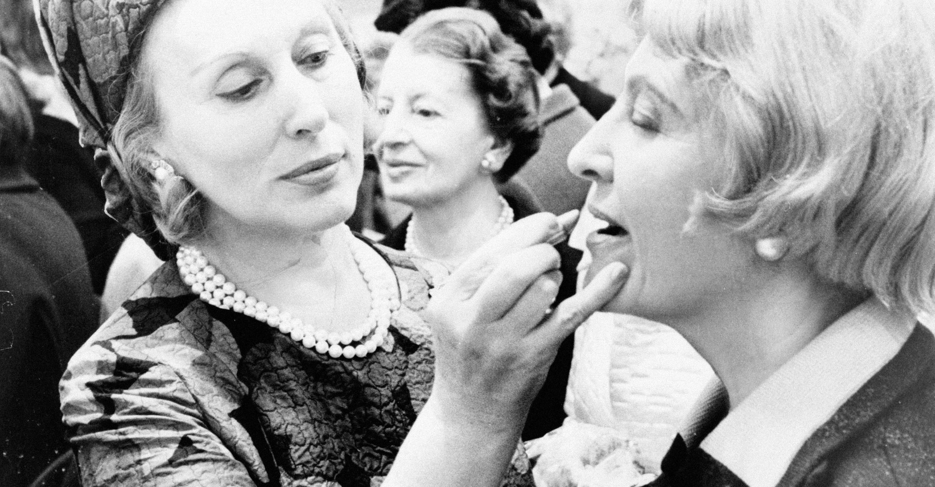 Eine Frau trägt einer anderen Frau Lippenstift auf