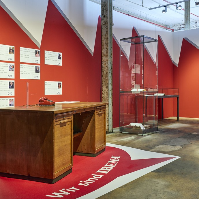 Holzschreibtisch in der IBENA Ausstellung vor rotem Hintergrund (vergrößerte Bildansicht wird geöffnet)