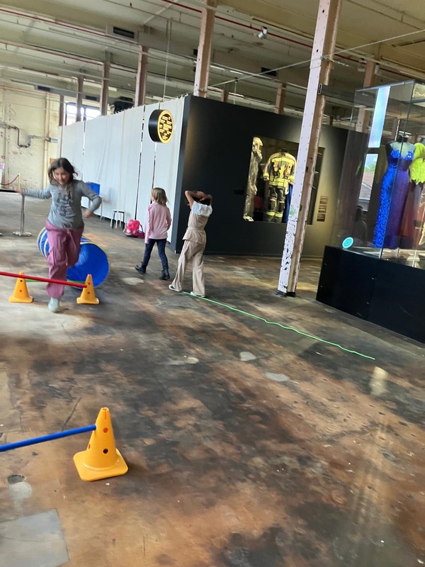 Kinder springen über verschiedene Hindernisse und balancieren über Seile am Boden.