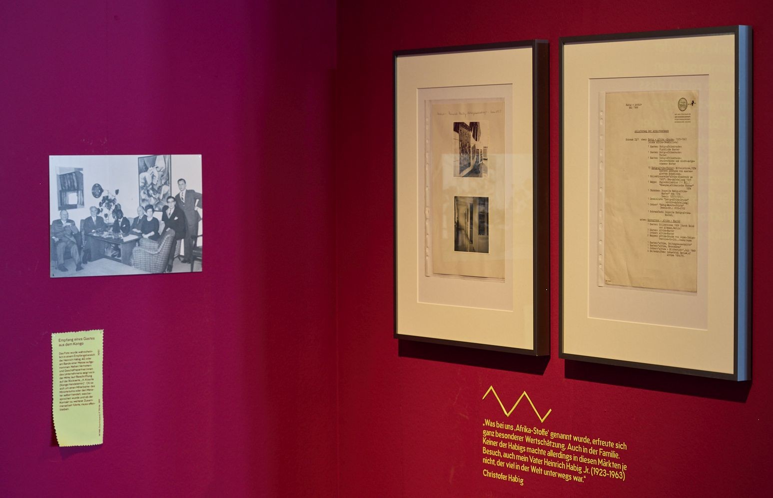 Rahmen mit Dokumenten an einer roten Ausstellungswand.