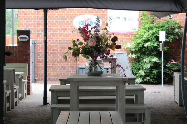 Weißer Holztisch mit Blumen vor dem Restaurantgebäude Schiffchen.