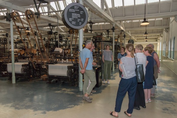 Blick in den Websaal: Historische Maschine und eine Besuchergruppe