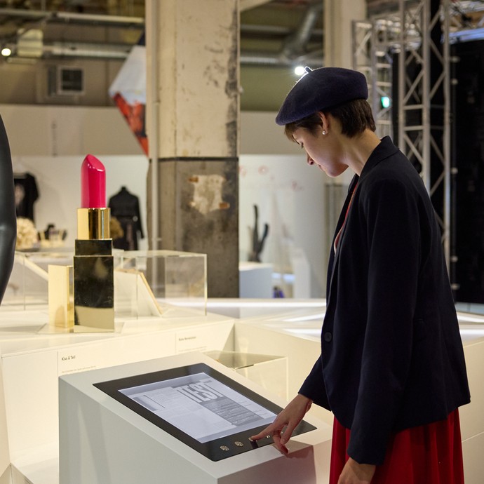 Frau schaut auf einen Touchscreen in der Ausstellung (vergrößerte Bildansicht wird geöffnet)